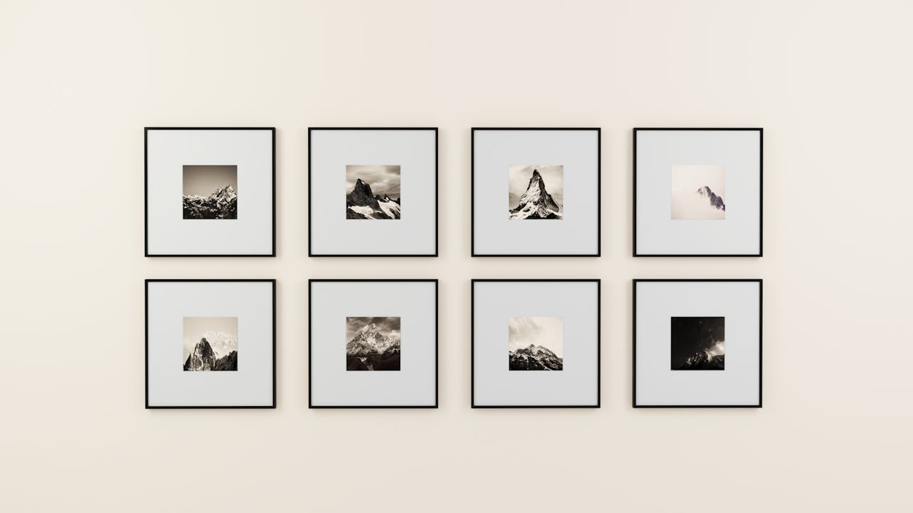 hero-img A minimalist display of framed mountain photography on a plain wall.